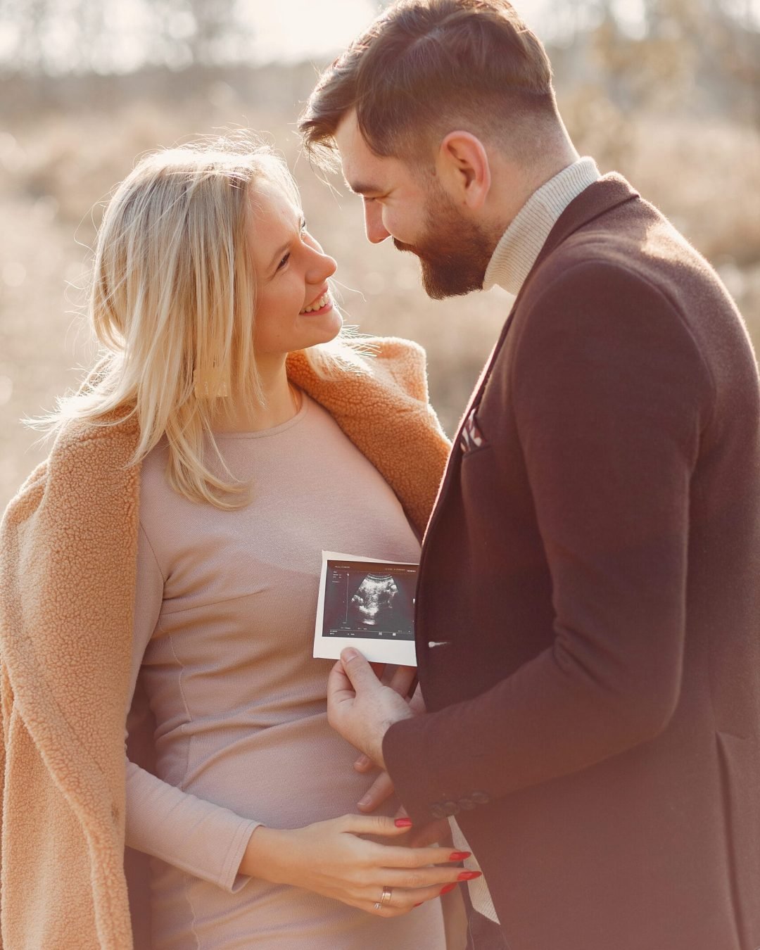 Woman in a brown coat. People in a spring forest. Family holding ultrasound.